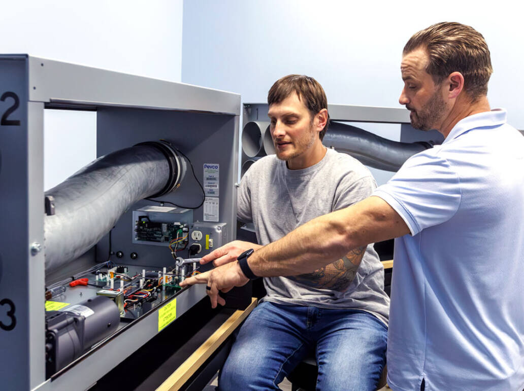 Two people working on part of the pneumatic tube system as part of the training class