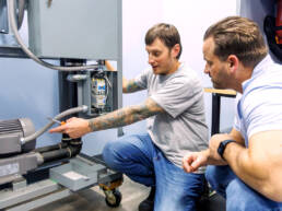 Two men working on part of the tube system as part of the training class